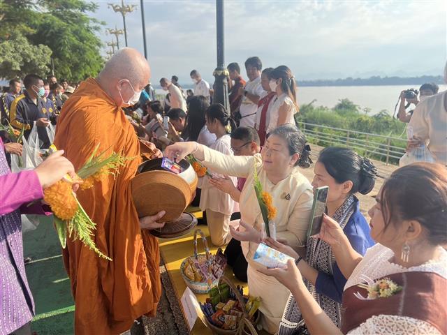 พช.นครพนม ร่วมใจพร้อมครอบครัวหิ้วตะกร้า ศรัทธาอิ่มบุญ อุดหนุนชุมชน : สวมผ้าไทย ห่มสไบ ใส่บาตรริมโขง